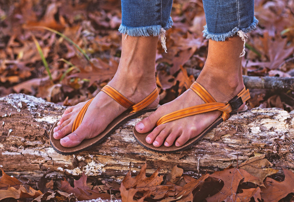 EarthRunners grounding sandals worn on a log in nature