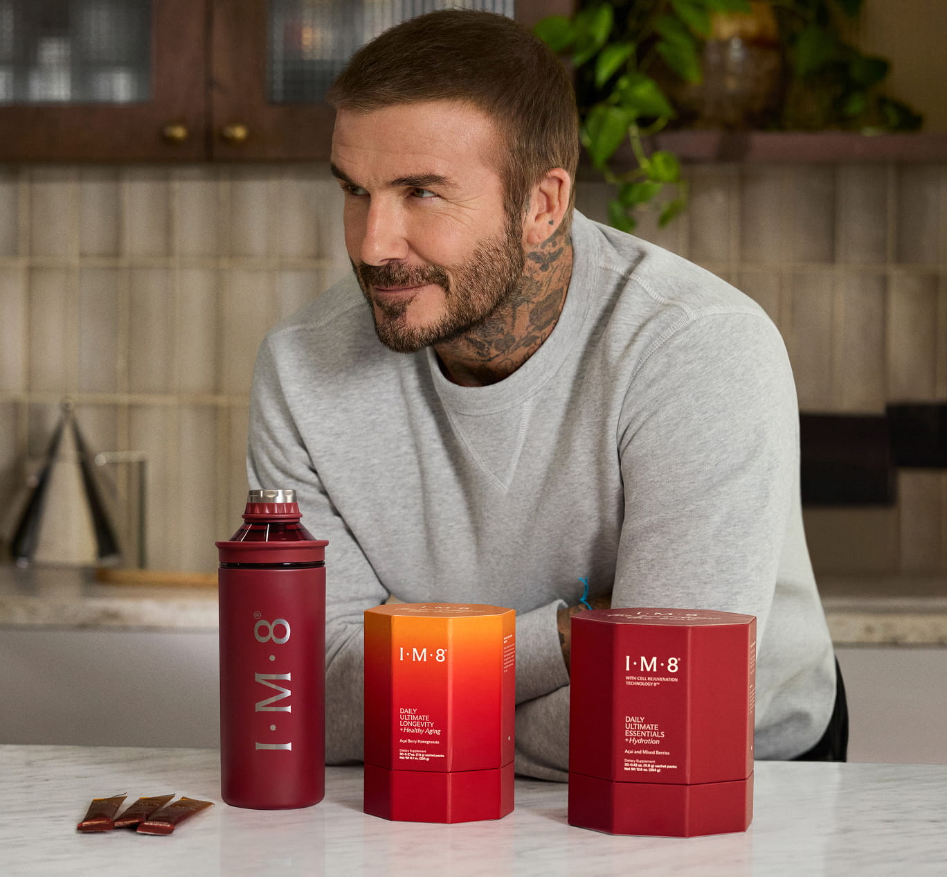 IM8 Essentials and Longevity product boxes with a red IM8 shaker bottle on a kitchen counter