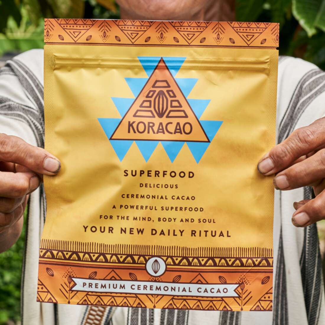 Indigenous farmer holding a Koracao ceremonial cacao superfood bag sourced from Peru and Colombia